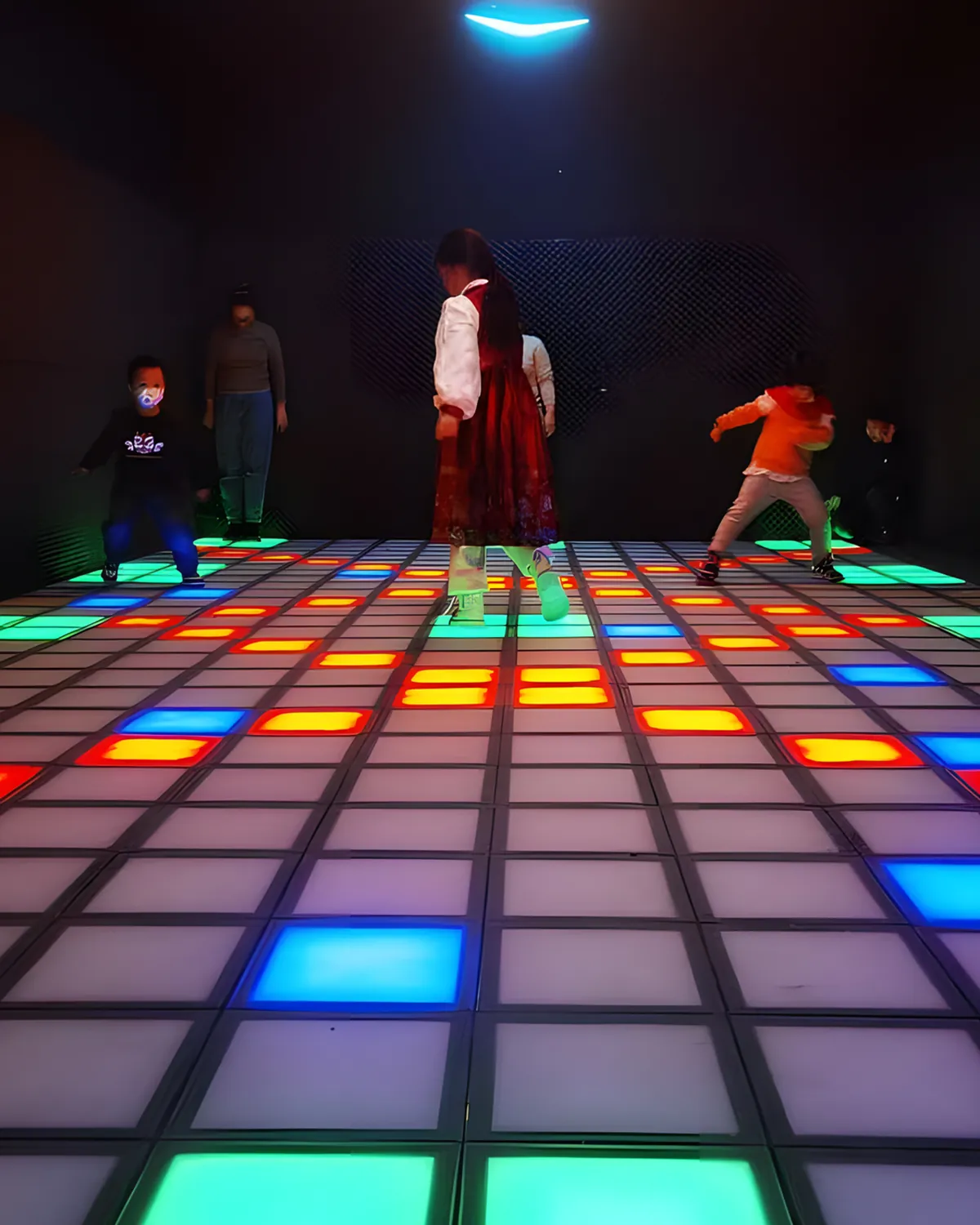Kids and parents playing floor is lava on a glowing LED tile floor