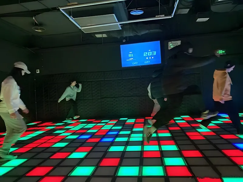 Friends mid-jump playing floor is lava on a red and green LED floor