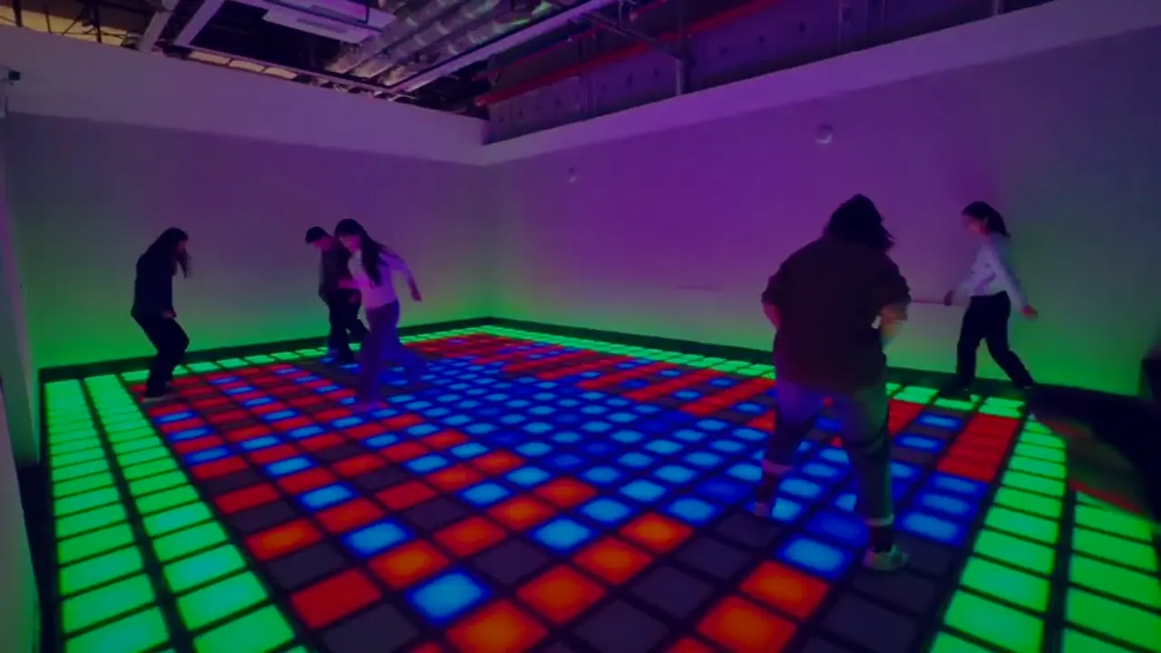 Colleagues spread across a red, blue and green LED floor during a floor is lava team building session at Lava Floor