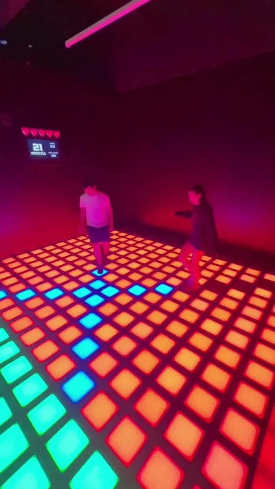 Two players on a pink and green LED floor at Lava Floor